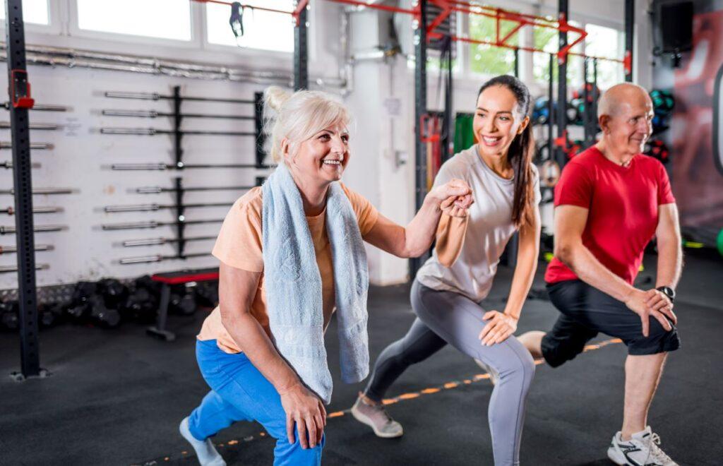 Ältere Frau und junger Mann beim Lunges-Training im Fitnessstudio zur Förderung der Gelenkgesundheit, unterstützt durch Glucosamin Chondroitin